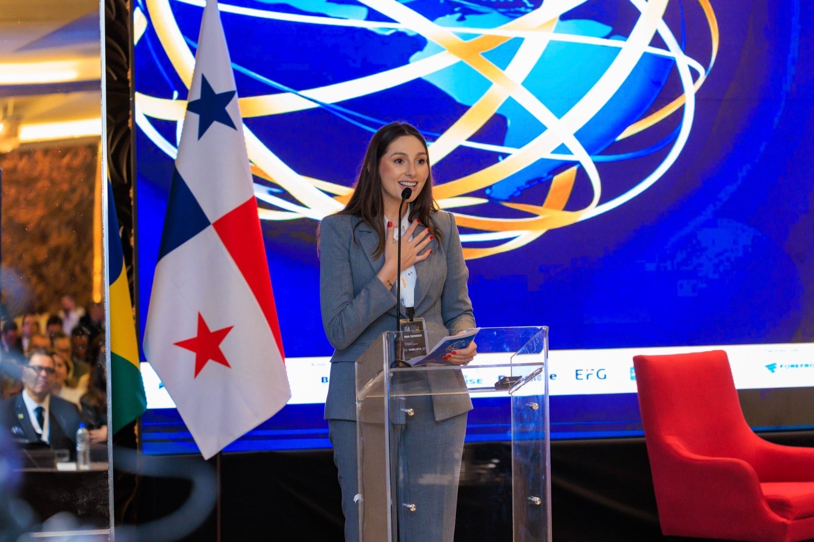 Nina Quisinski speaks at a lectern during an event, alongside the flag of Panama.